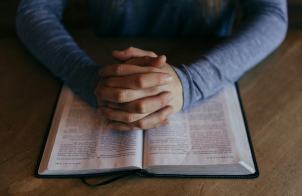 man holding his hands on open book